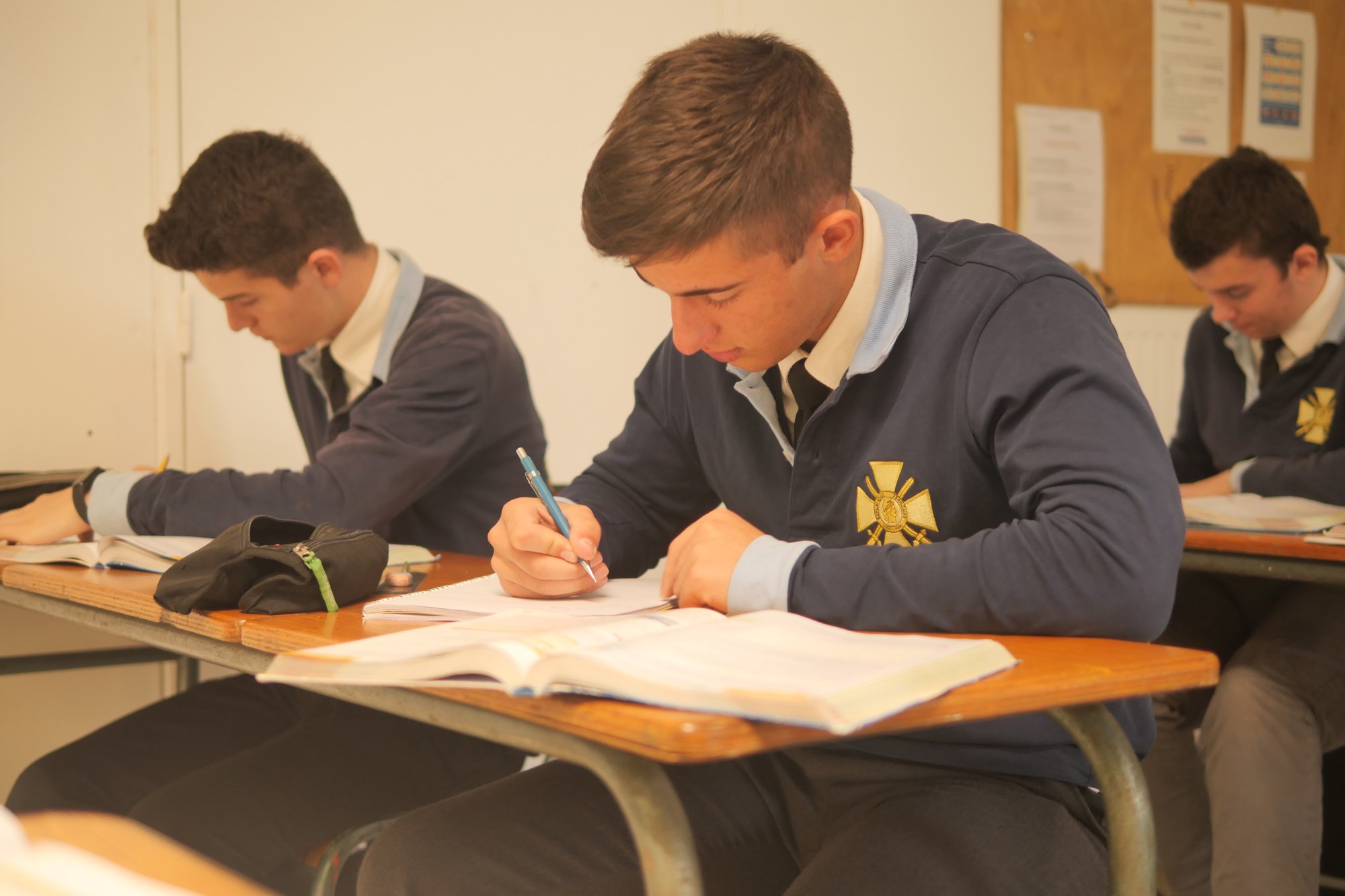 Lycéens en uniforme concentrés sur leur travail écrit en salle de classe