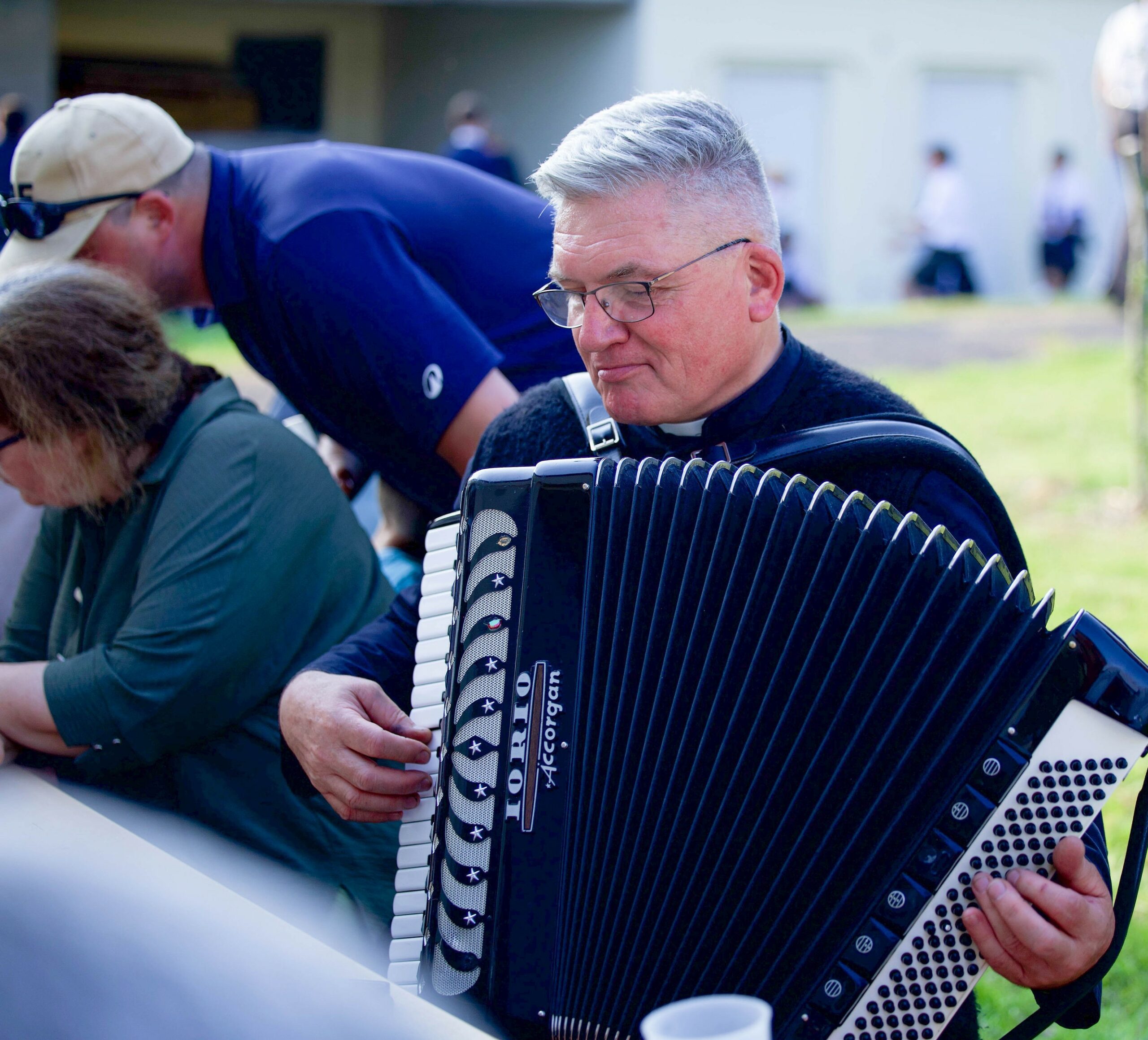 Un abbé joue de l’accordéon lors d’une fête de l’école