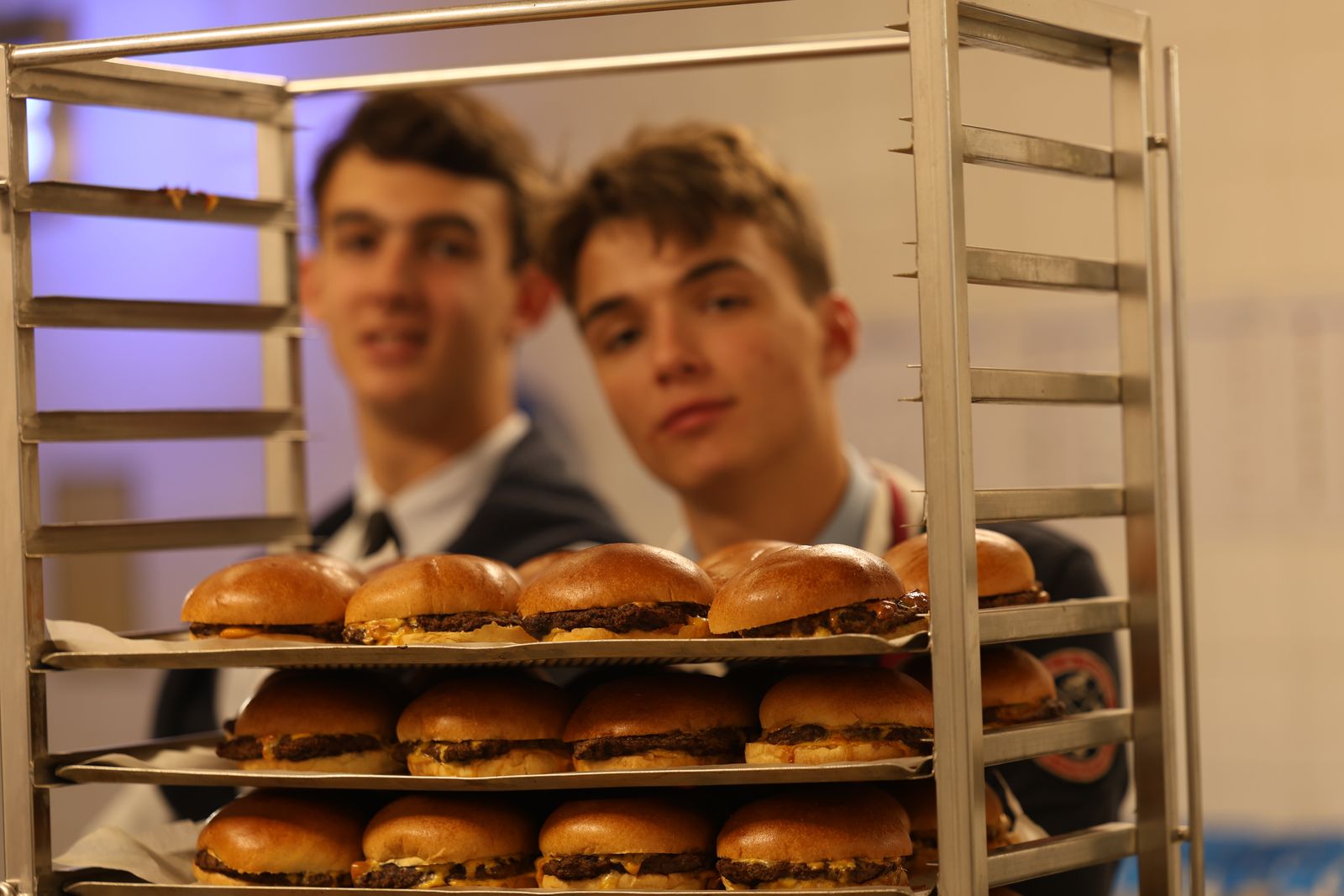 Deux élèves derrière un chariot de burgers préparés pour la fête