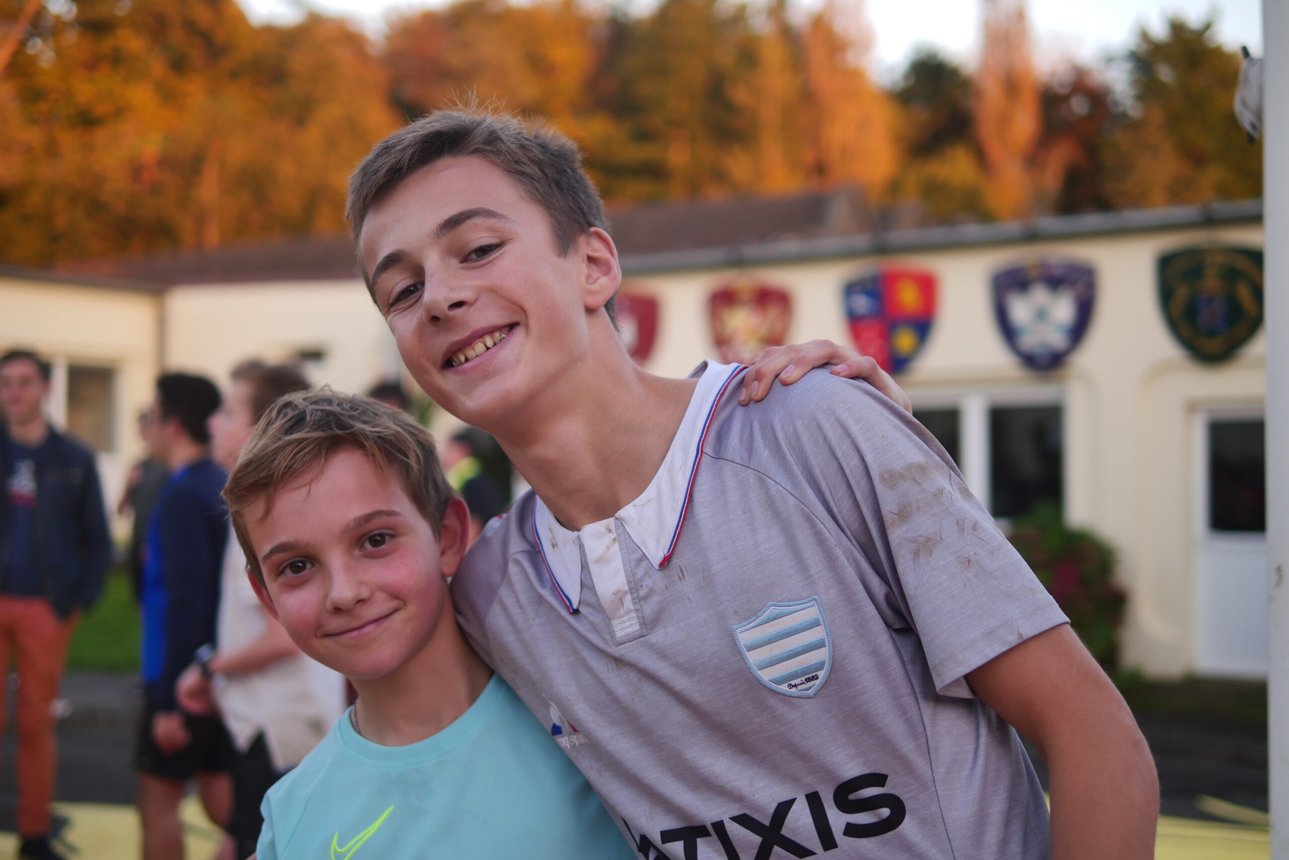 Deux élèves souriants après un match, devant les écussons des maisons