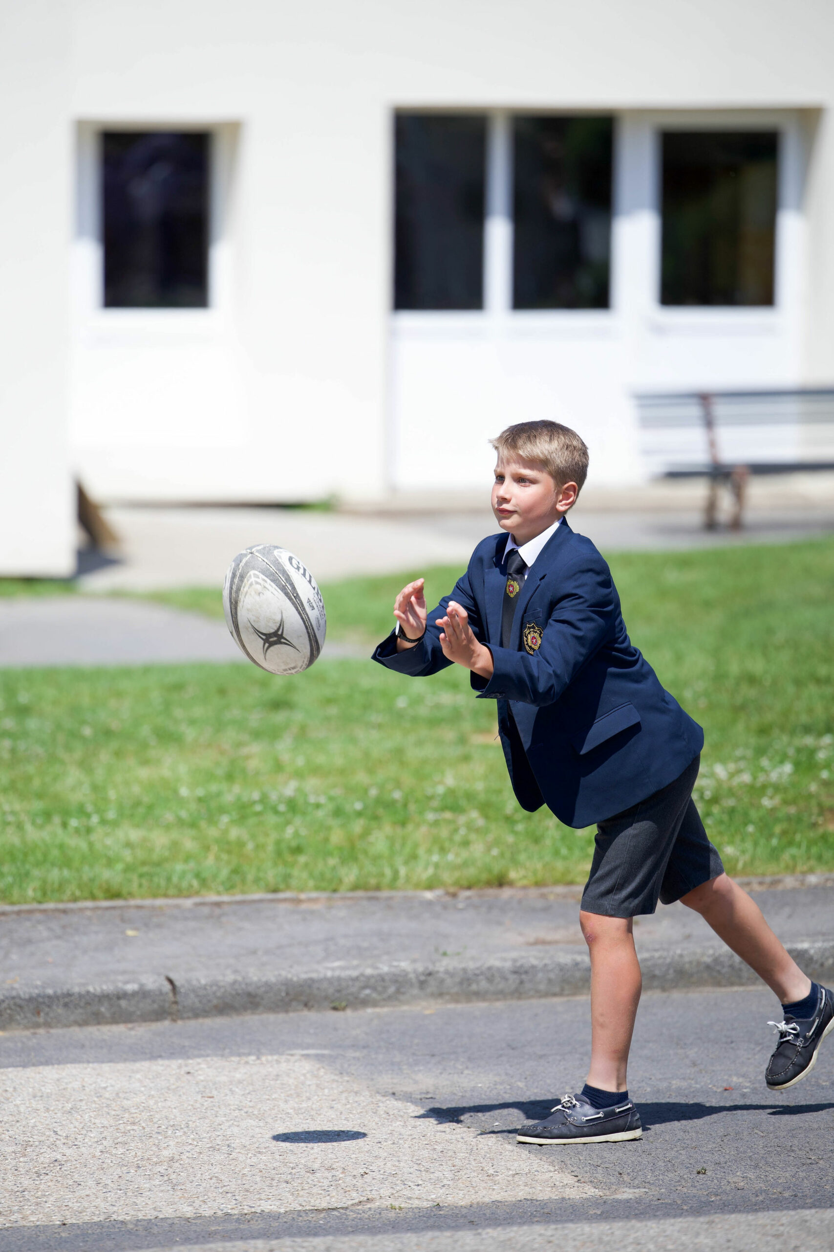 Élève en uniforme faisant une passe de rugby dans la cour