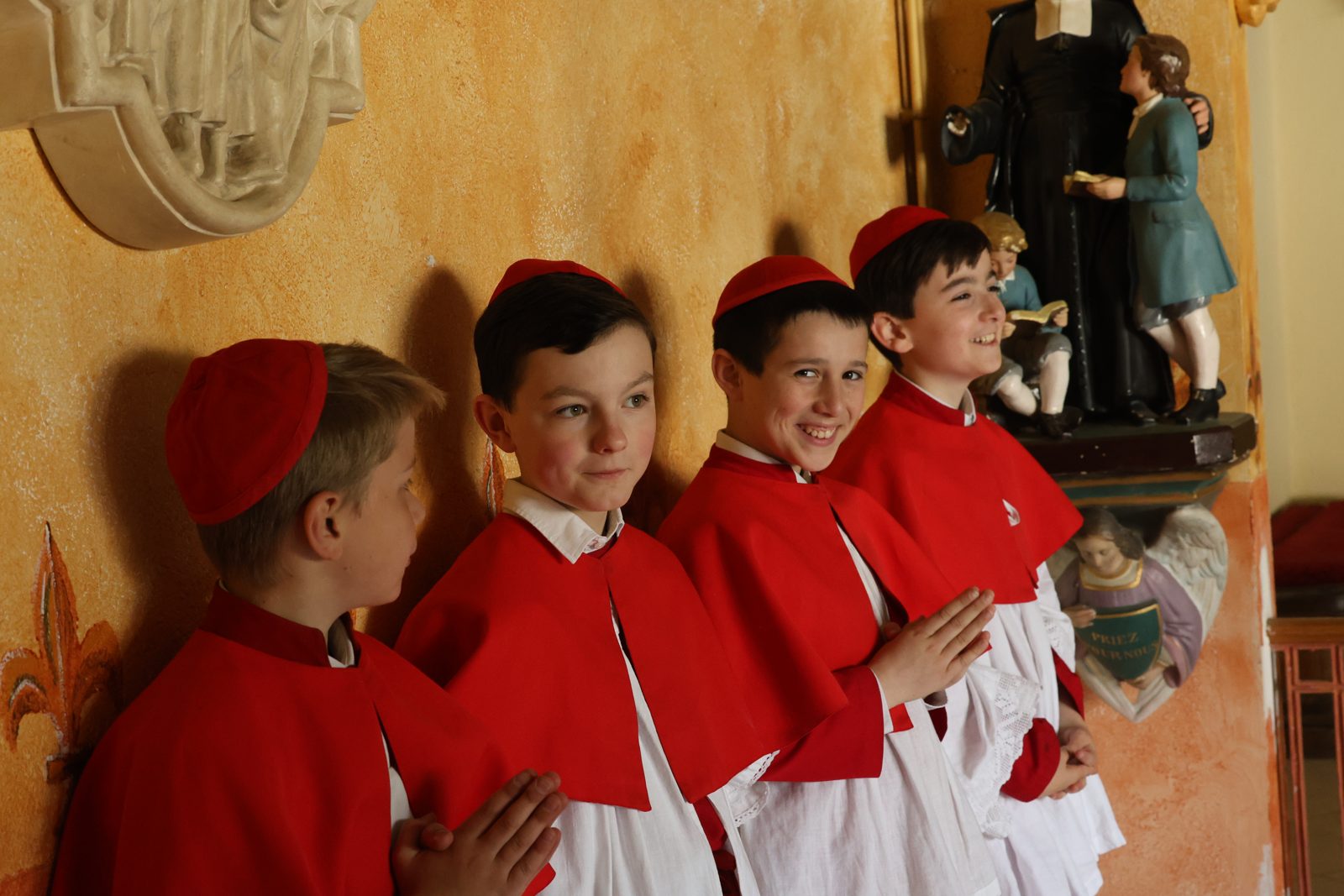 Servants de messe en aube et camail rouges dans la chapelle