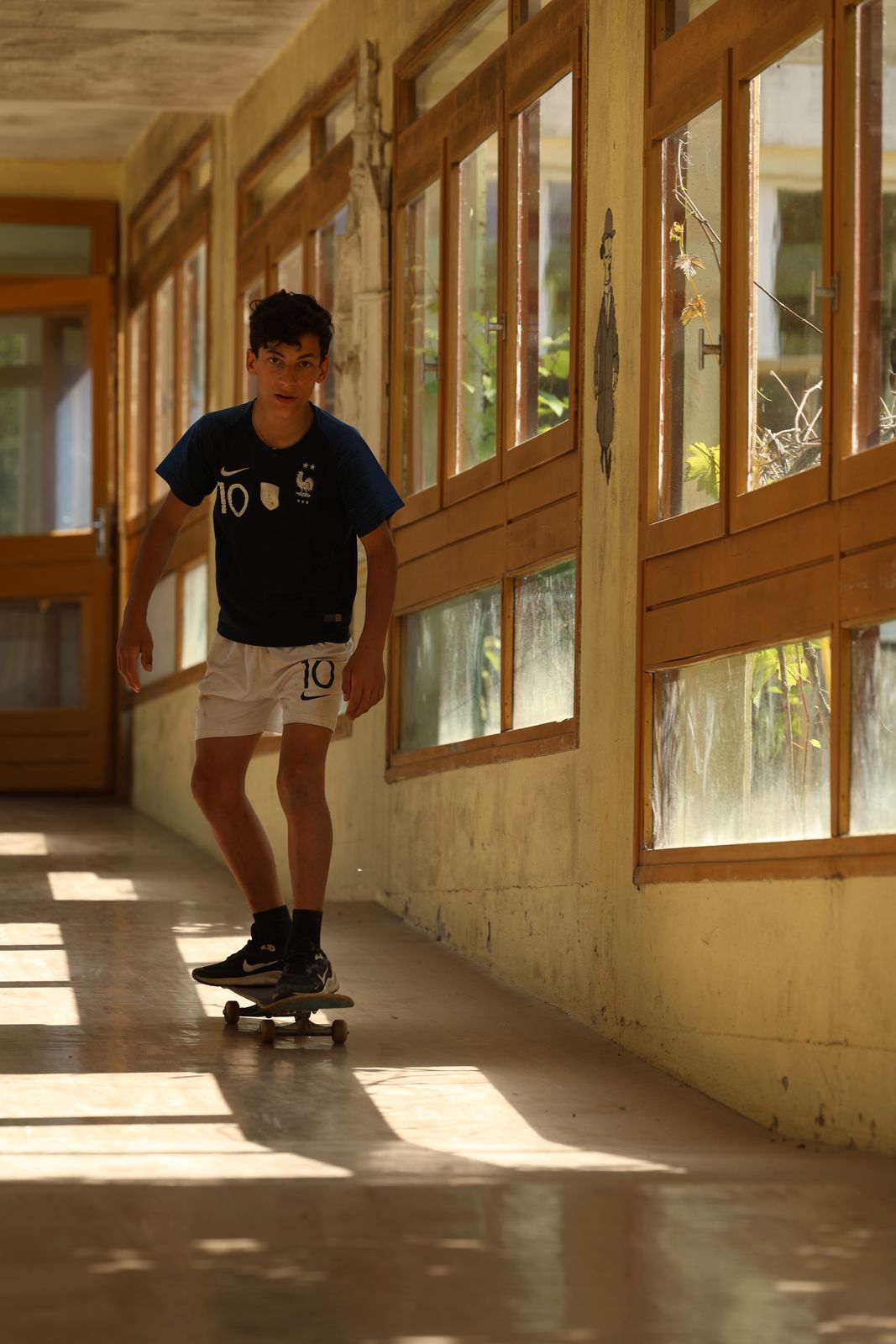 Élève en skateboard dans un couloir ensoleillé de l’école